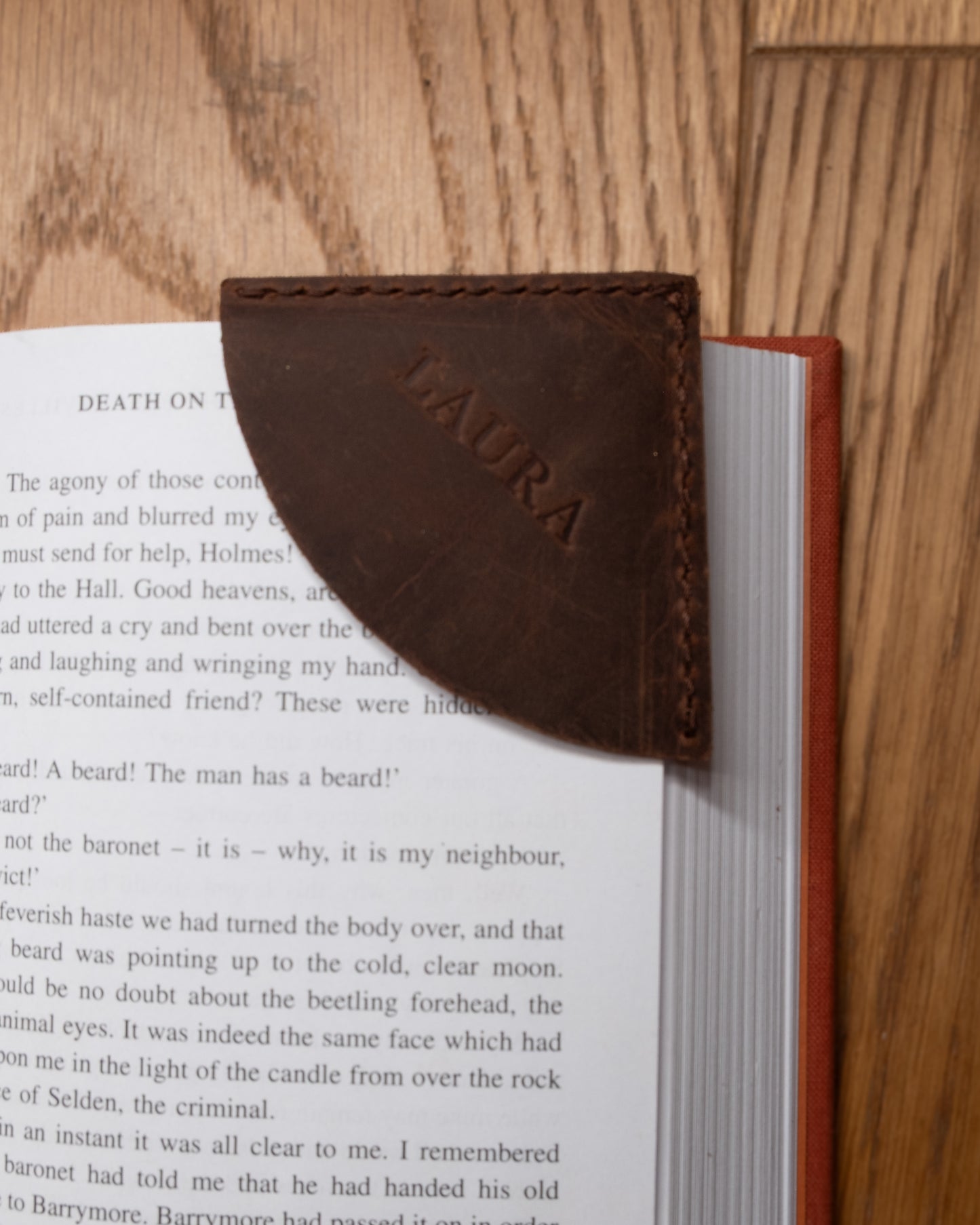 Personalised brown top grain crazy leather corner bookmark placed on an open book