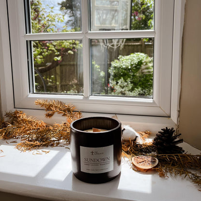 Sundown hand-poured soy candle displayed on a sunlit windowsill with natural botanical decor