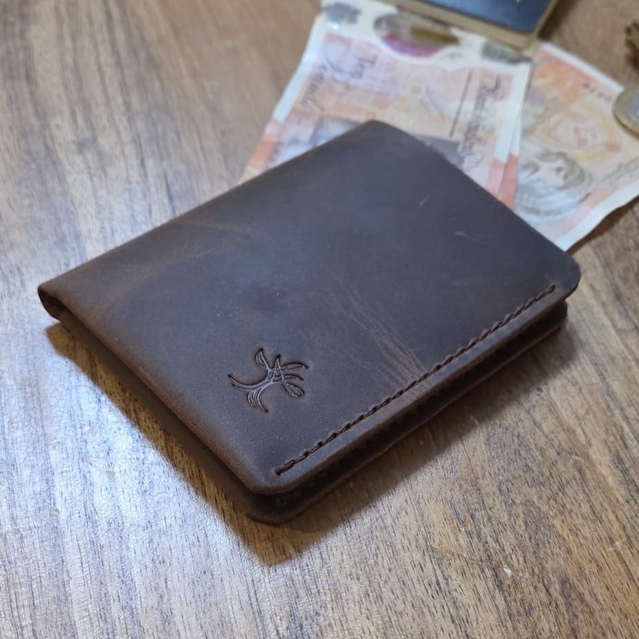 Brown top grain crazy leather Card Holder beside banknotes and coins on a wooden surface