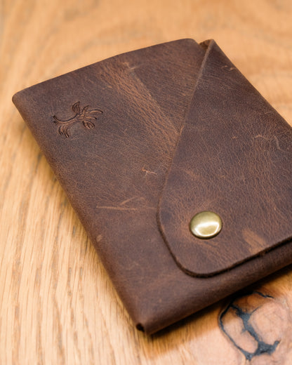 Close-up of brown top grain crazy leather Minimalist Wallet showing leather texture, embossed logo and brass snap closure