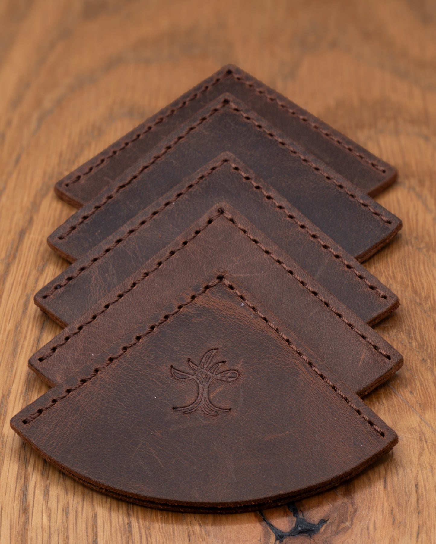 Four brown top grain crazy leather corner bookmarks stacked on a wooden surface