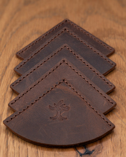 Four brown top grain crazy leather corner bookmarks stacked on a wooden surface
