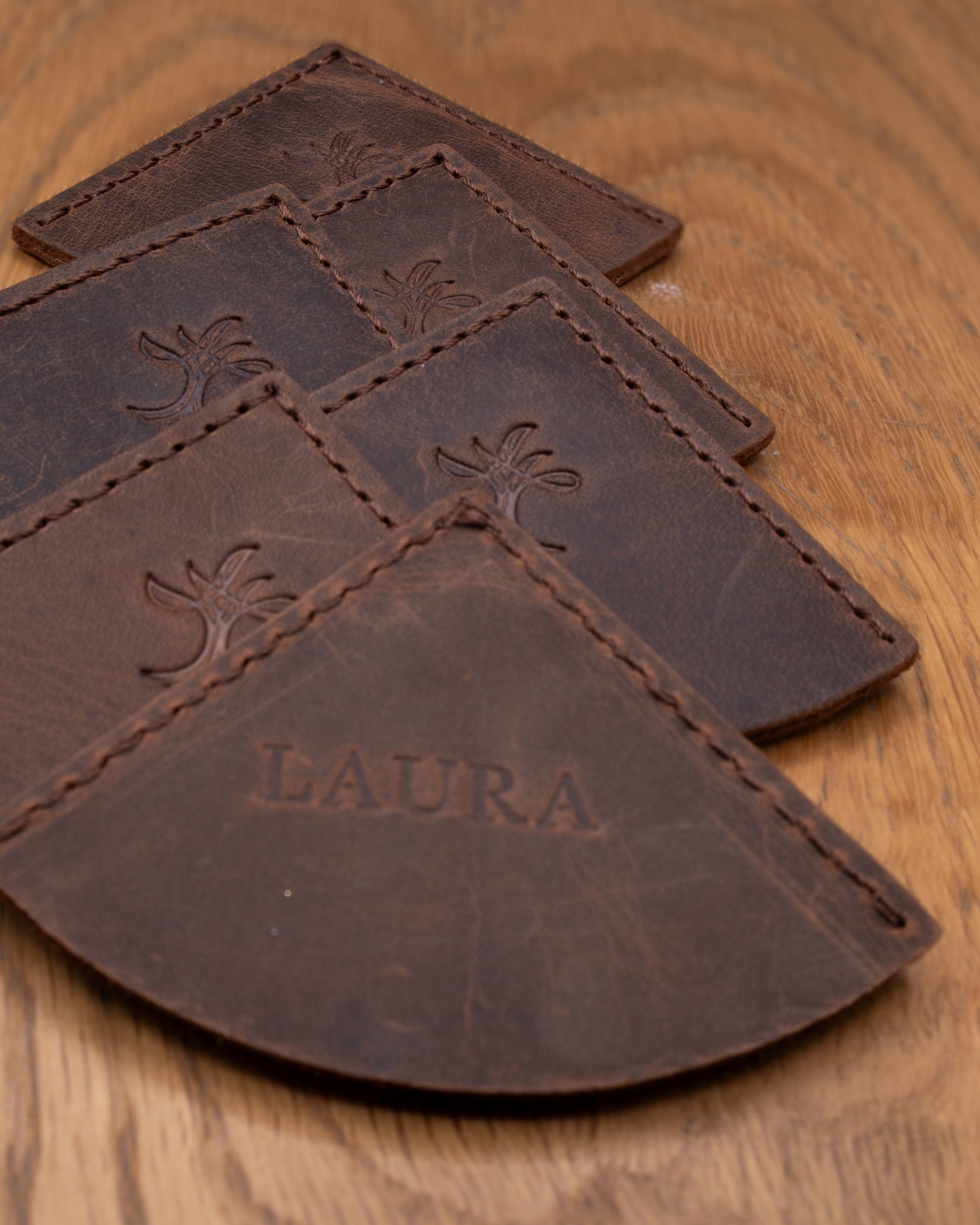 Brown top grain crazy leather corner bookmarks with one personalised bookmark on a wooden surface