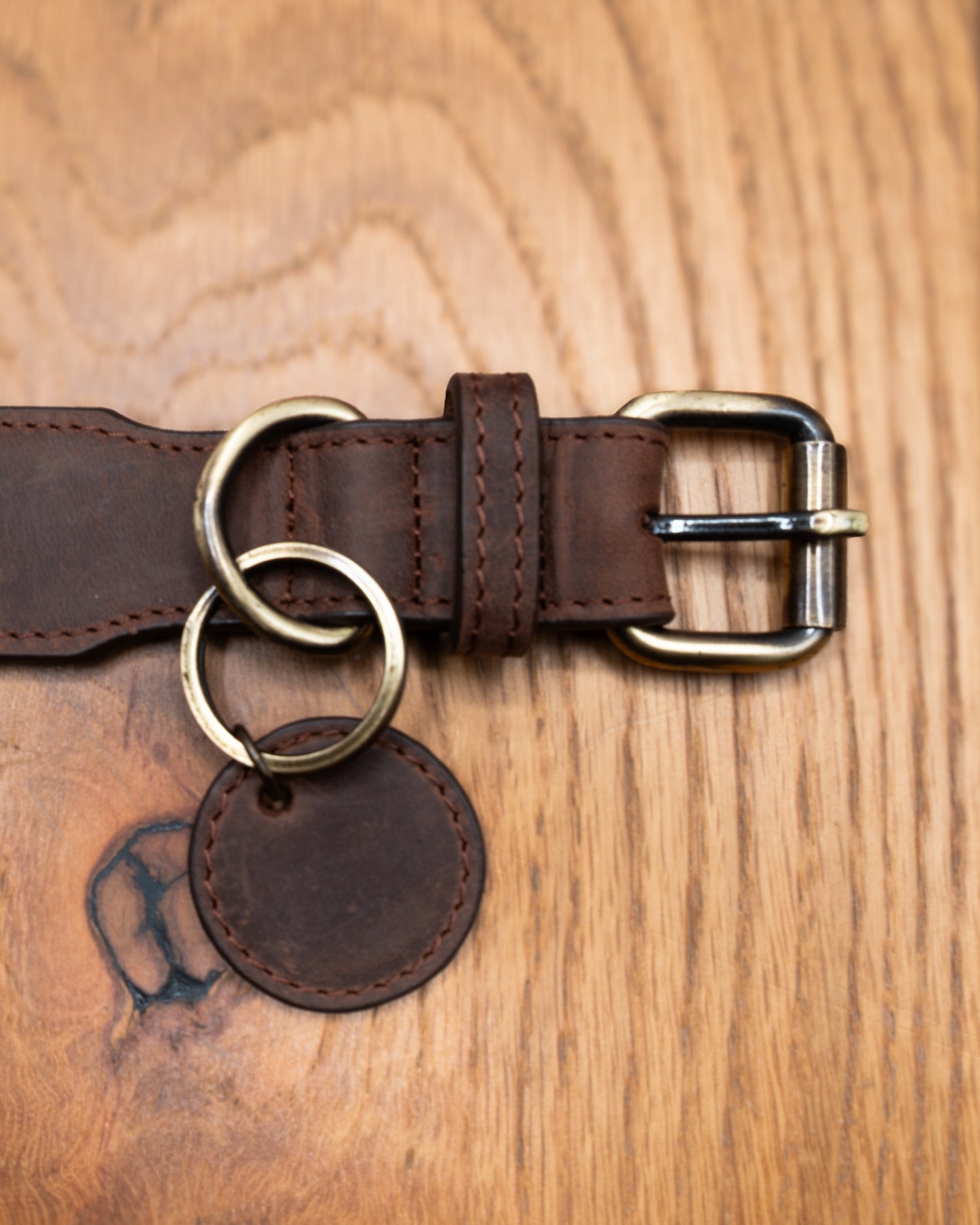 Top-down close-up of brown top grain crazy leather Dog Collar with brass buckle, D-ring and decorative leather charm