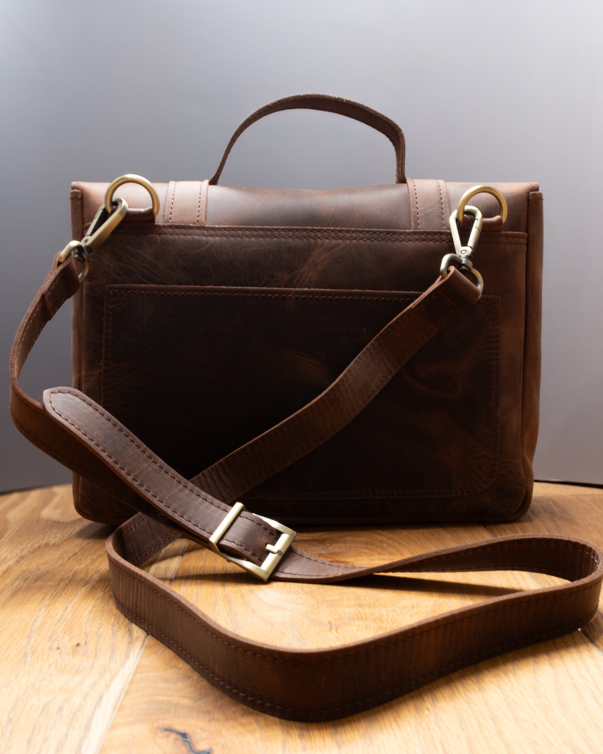 Back view of Postman Bag in brown Top Grain Crazy Leather with adjustable shoulder strap and rear pocket