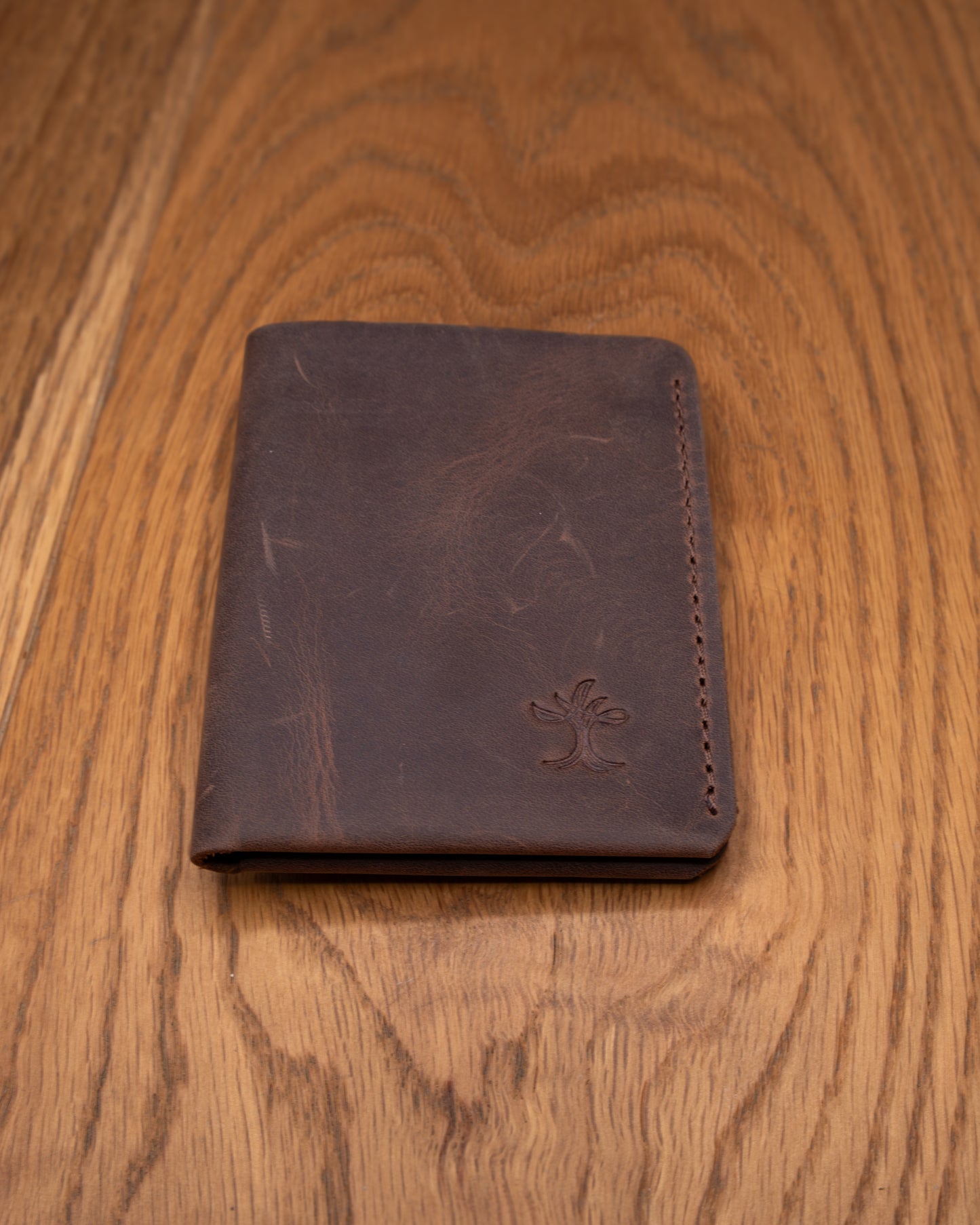 Brown top grain crazy leather Card Holder shown from a wider front view on a wooden surface