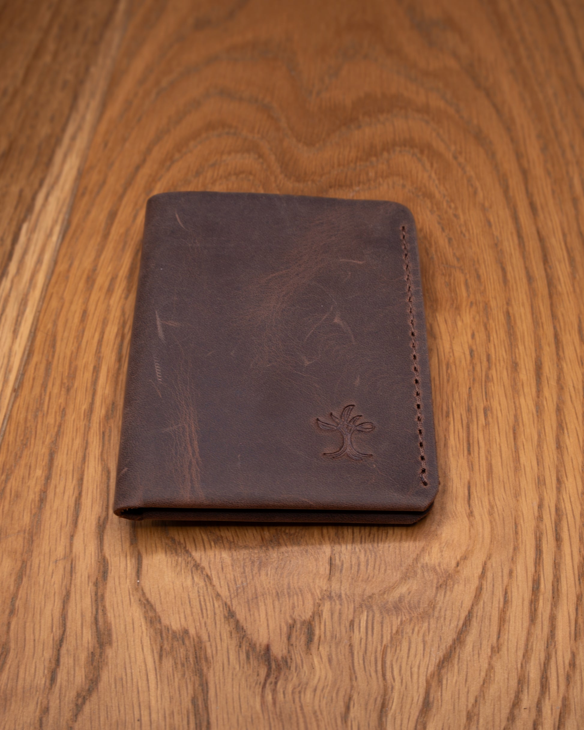 Brown top grain crazy leather Card Holder shown from a wider front view on a wooden surface