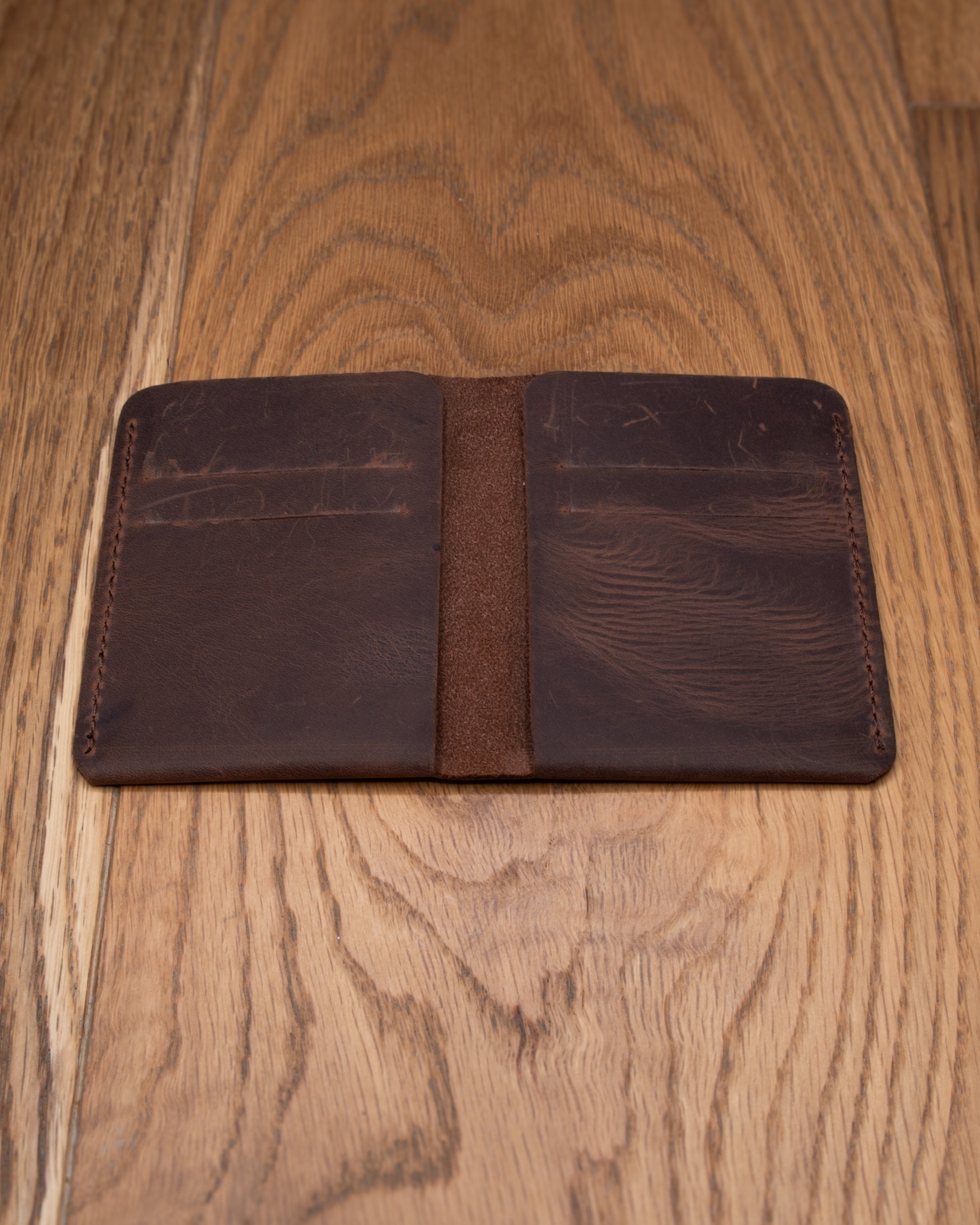 Open brown top grain crazy leather Card Holder showing four interior card slots on a wooden surface