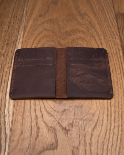 Open brown top grain crazy leather Card Holder showing four interior card slots on a wooden surface