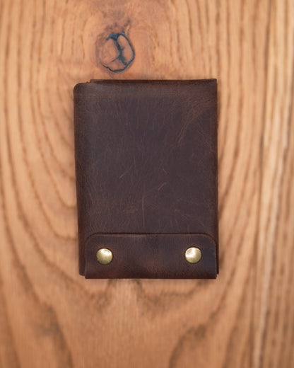 Back view of brown top grain crazy leather Minimalist Wallet with two brass rivets on a wooden surface