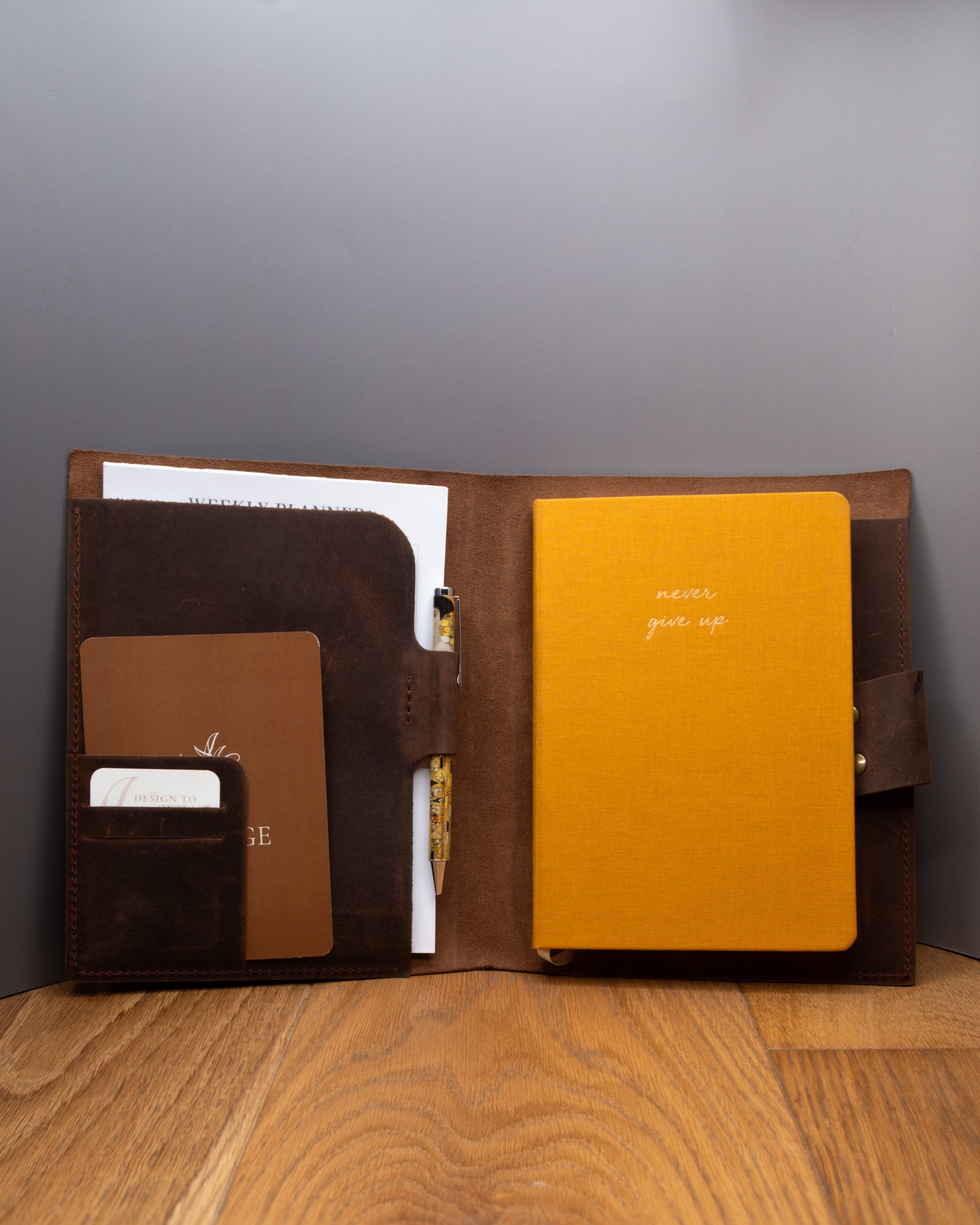 Open brown top grain crazy leather Notebook Cover holding a notebook, planner, cards and pens