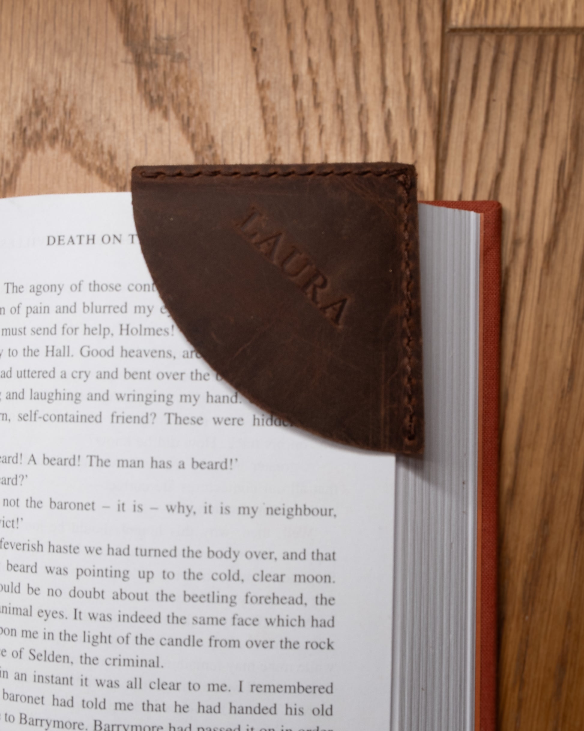 Personalised brown top grain crazy leather corner bookmark placed on an open book